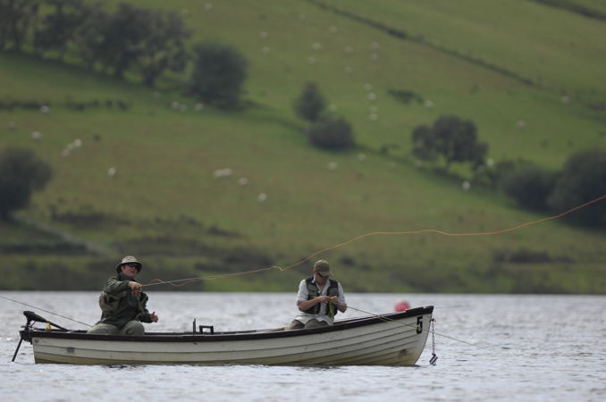 Eisteddodd dau ddyn mewn cwch ar bysgota afon Eisteddodd dau ddyn mewn cwch ar bysgota afon